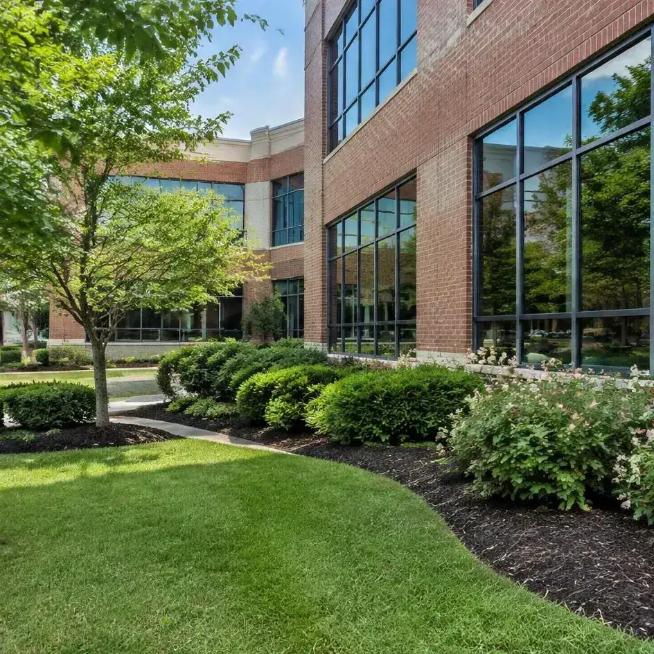 Office courtyard lawn and shrub beds beside a glass-and-brick commercial building