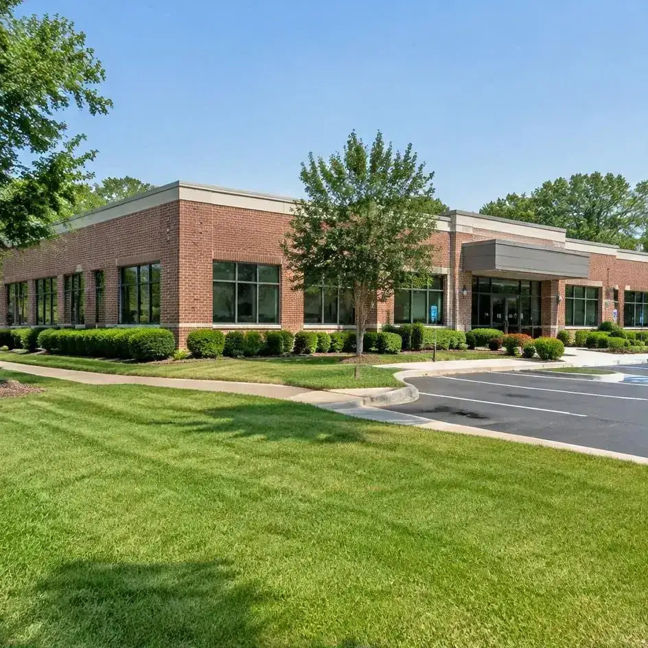 Commercial office building with maintained lawn, shrubs, and parking-area landscaping